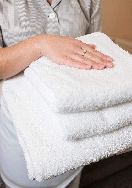 close-up-female-chambermaid-holding-clean-soft-folded-towel-hand-banner-4